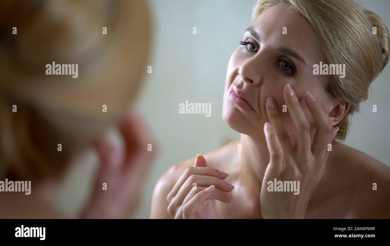 Preoccupato della donna cercando di smooth rughe, face lifting, chirurgia plastica concept Foto Stock