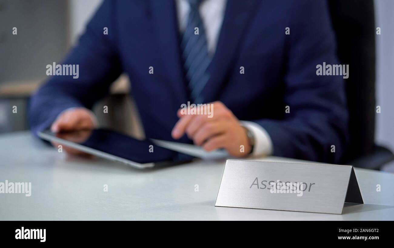 Assessore maschio lavora su tablet pc, occupato con dei costi di proprietà e di valutazione fiscale Foto Stock