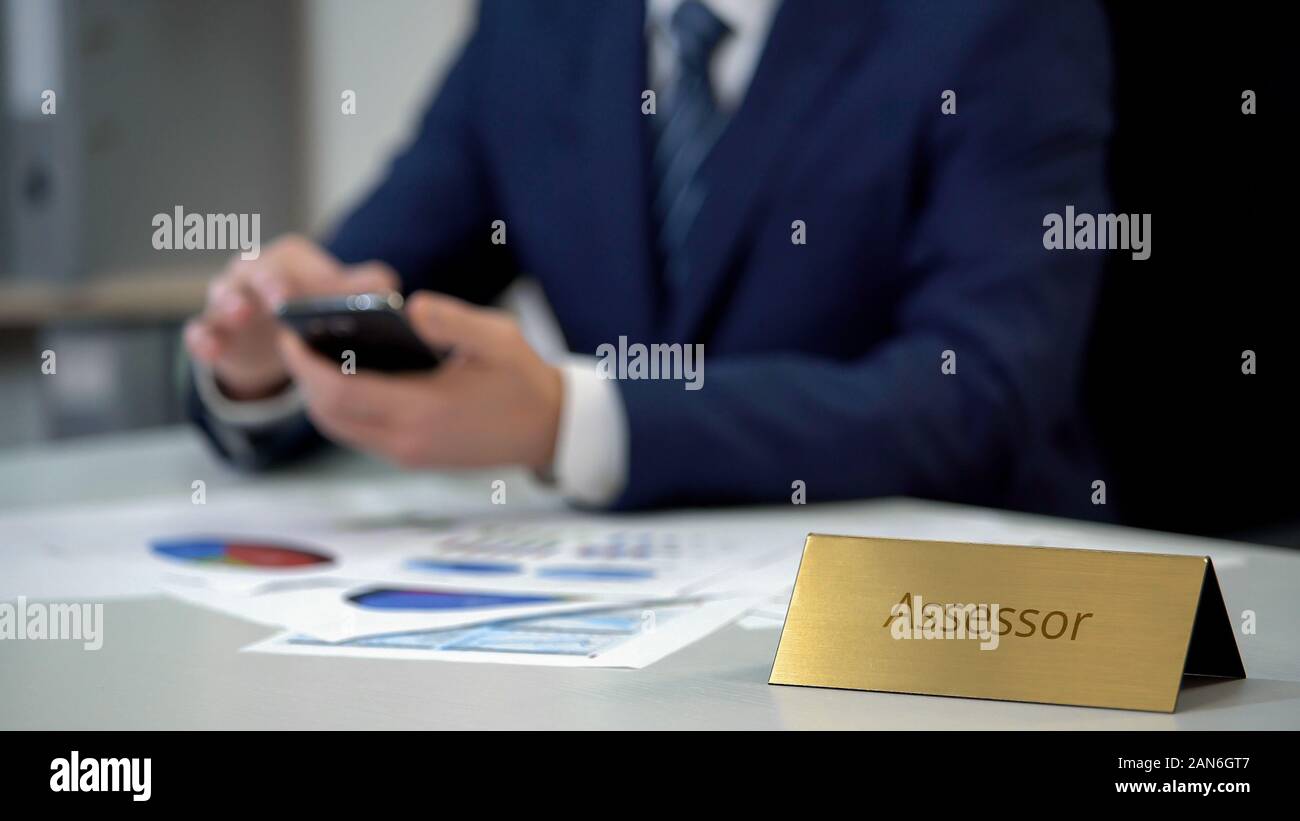 Assessore maschio in business suit utilizza lo smartphone, lavorare su documenti importanti Foto Stock