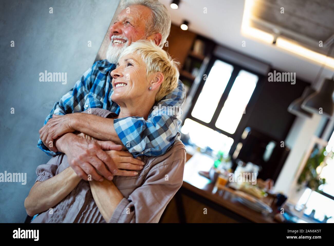 Sorridenti coppia senior abbracciando insieme a casa Foto Stock