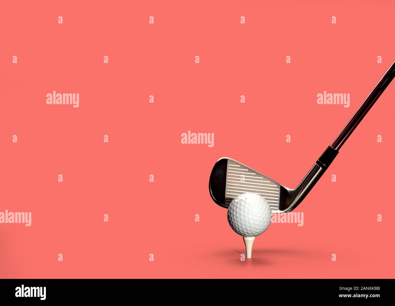 Palla da golf sul tee, solido background di corallo Foto Stock