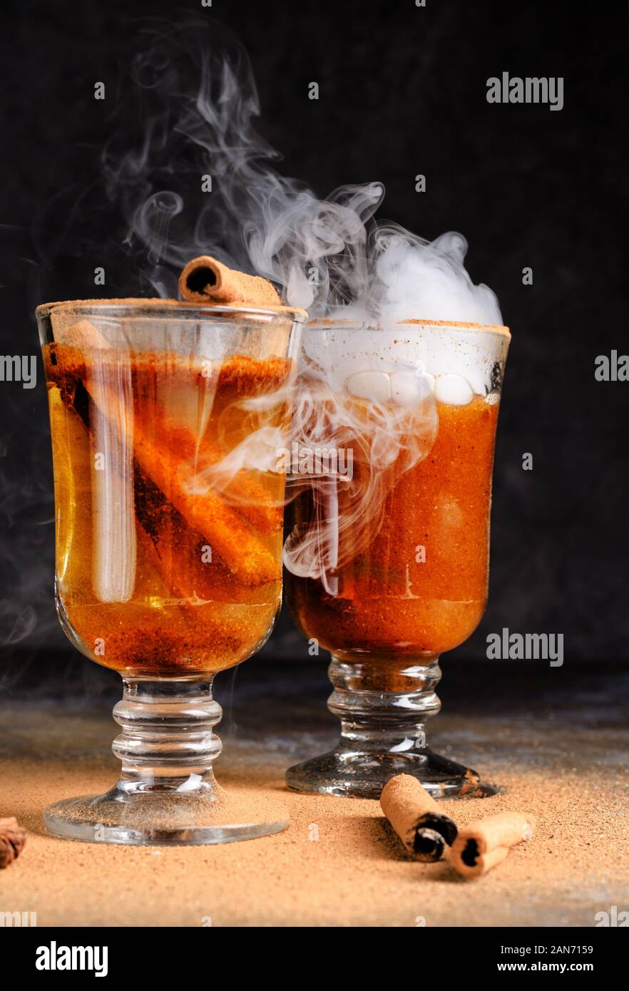 Vin brulé alla cannella in bere due bicchieri di vetro con vapore bianco. Dark moody cibo ancora in vita. Foto Stock