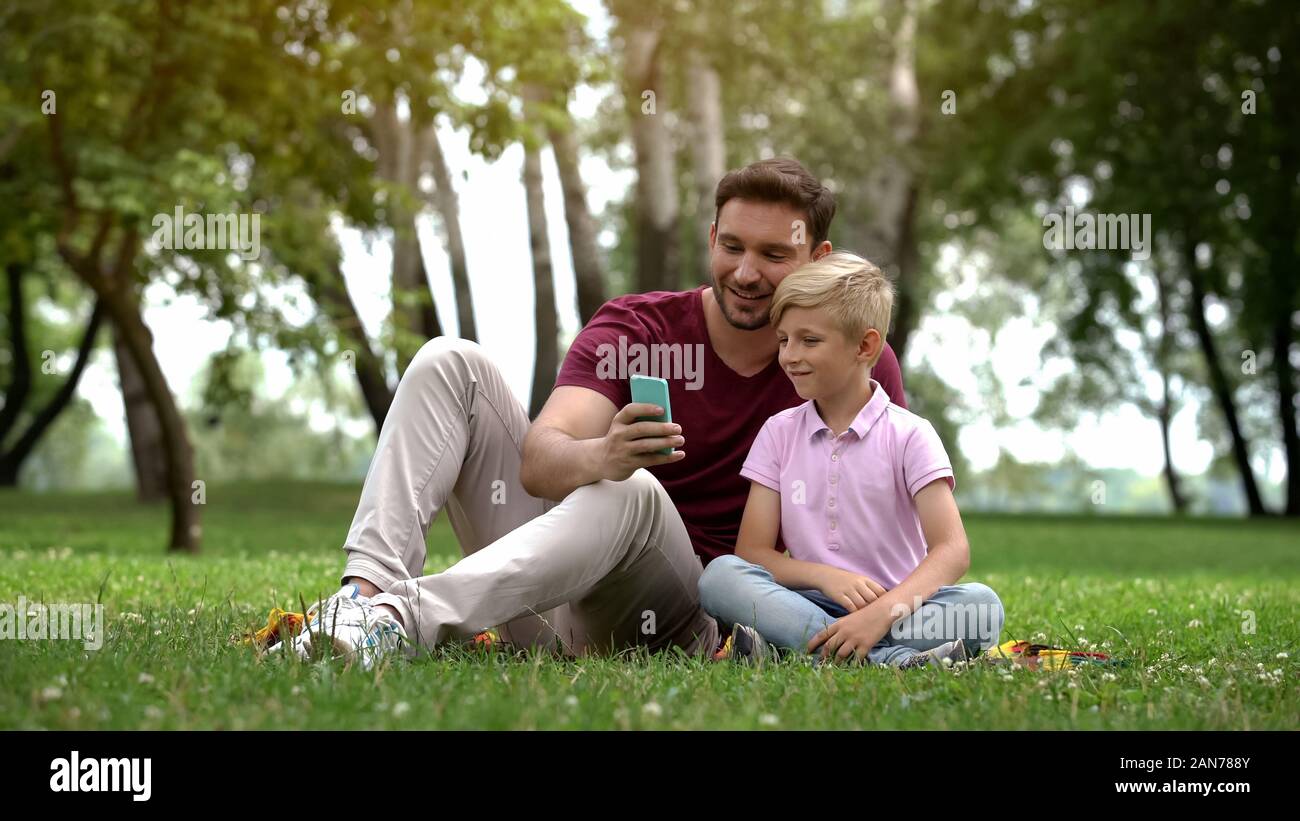 Papà e figlio di parlare con i parenti tramite smartphone, video conferenza, 4g internet Foto Stock