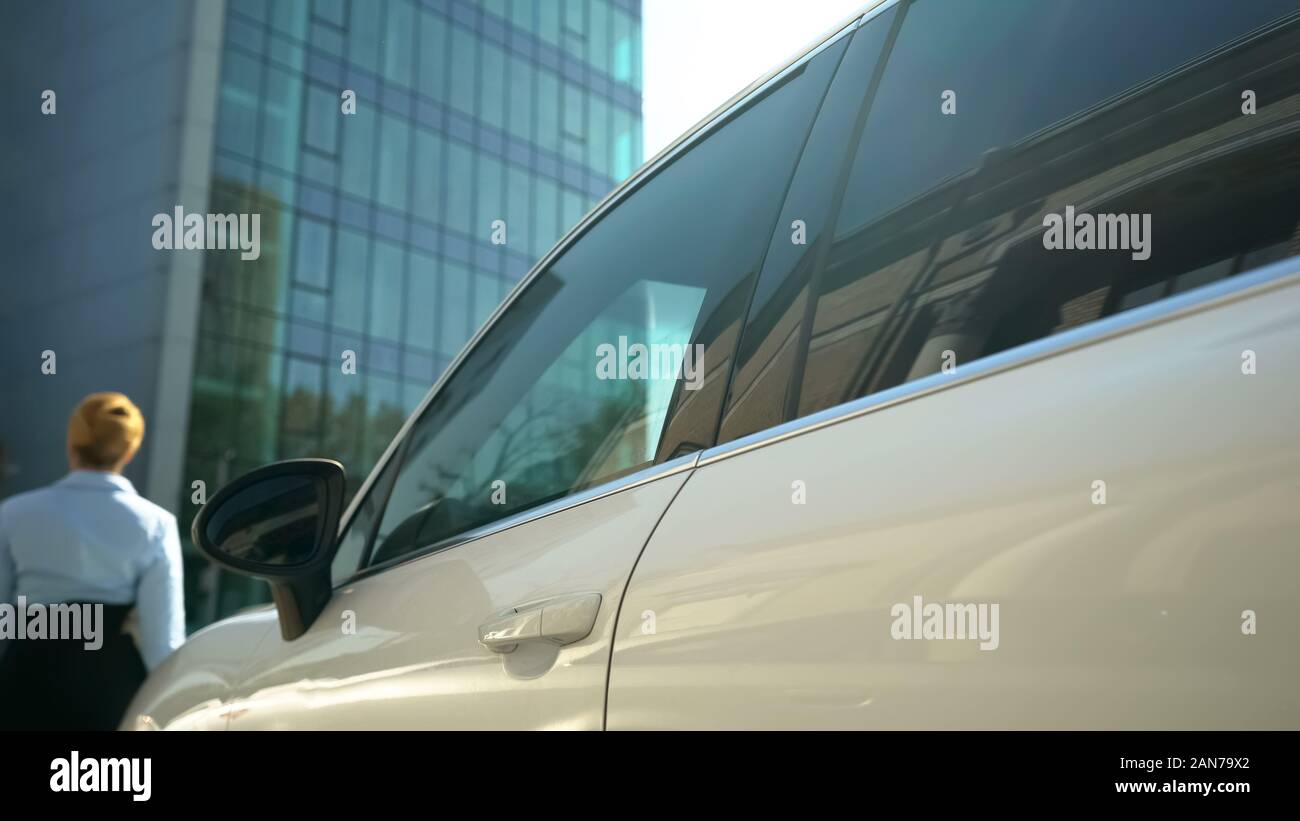 Business donna a piedi dalla sua auto in edificio per uffici, carriera e patrimonio Foto Stock