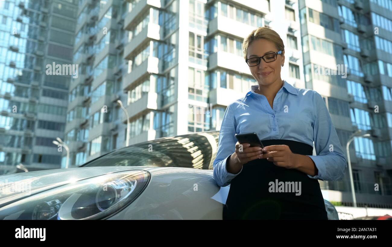 Imprenditrice controllo messaggio sul cellulare sorridente, il successo nella vita e nel lavoro Foto Stock