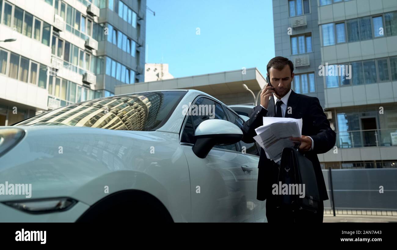 Imprenditore parlando al telefono vicino auto, risolvere i problemi finanziari della società Foto Stock