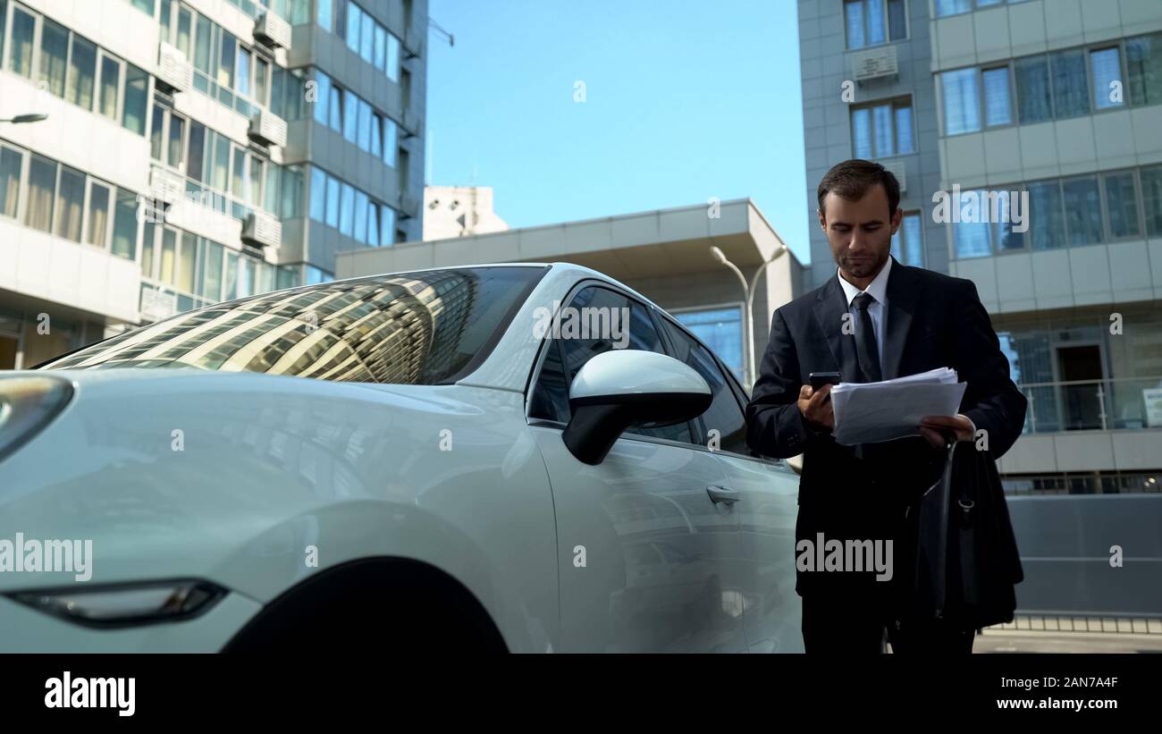 Commercianti la lettura dei messaggi di posta elettronica sul telefono vicino auto, problematiche aziendali della società Foto Stock