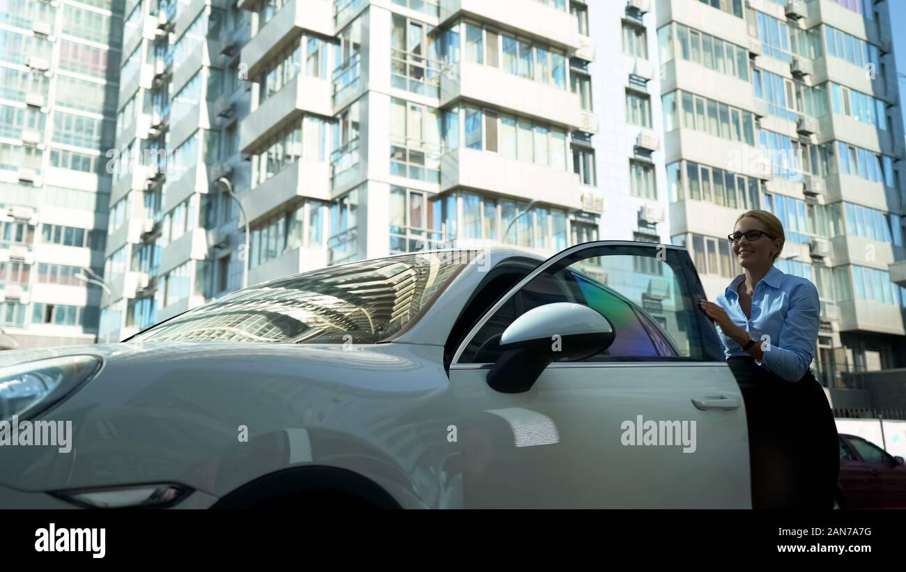 Felice signora esce di auto di lusso, carriera di successo e ricchezza, acquistare auto Foto Stock