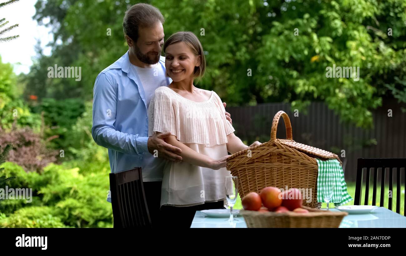 Romantico picnic in country house, marito abbracciando la moglie, felice offerta famiglia Foto Stock
