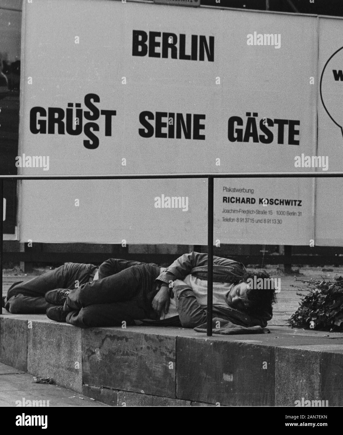 01 gennaio 1982, Berlin: sotto un poster pubblicitario in Berlin-Charlottenburgl giace un uomo. Foto: Paul Glaser/dpa-Zentralbild/ZB Foto Stock