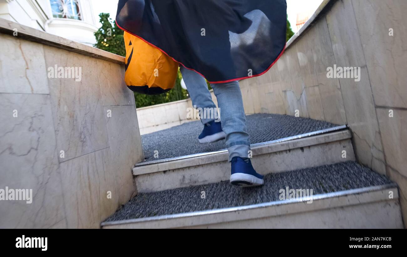 Il capretto con Trick or Treat bag in esecuzione al piano di sopra di casa confinante per caramelle Foto Stock