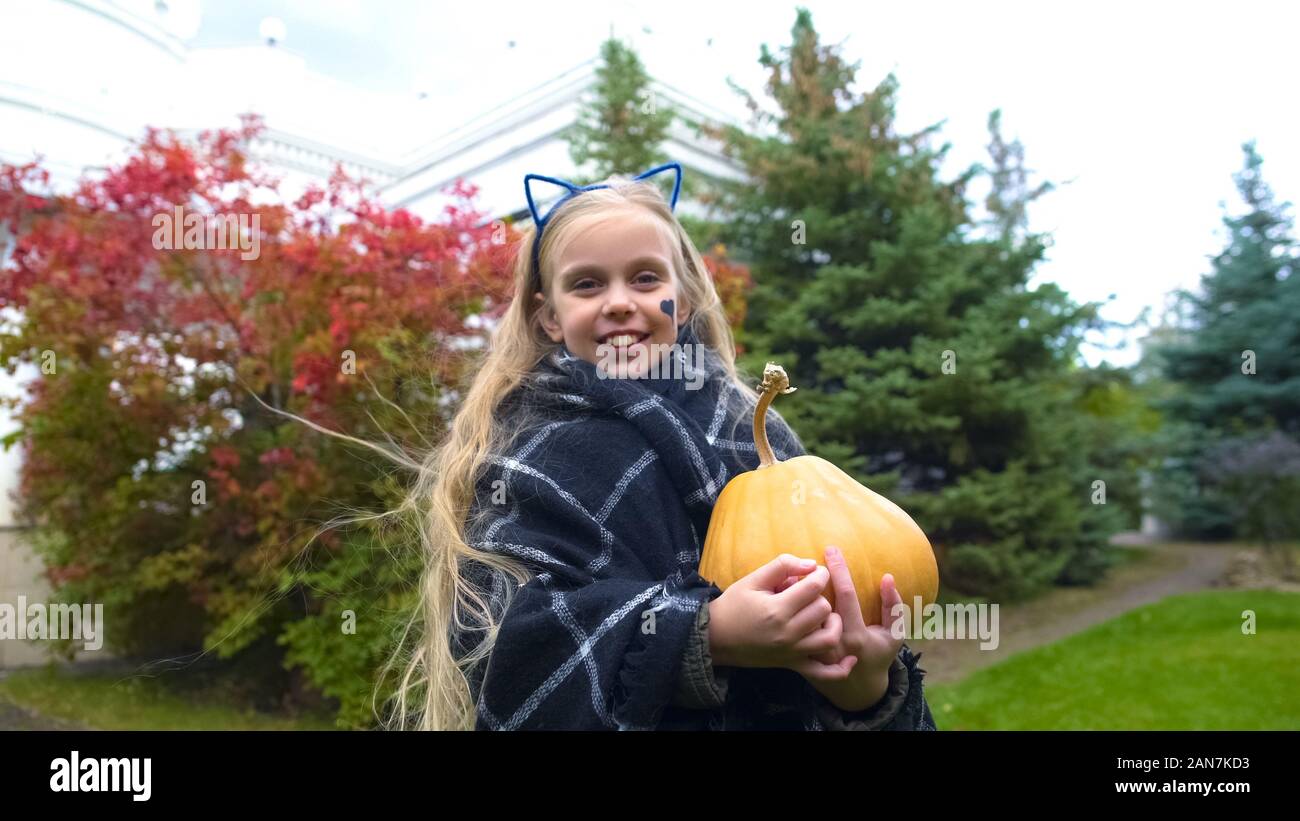 Felice ragazza con zucca e posa per telecamera in Halloween costume cat Foto Stock