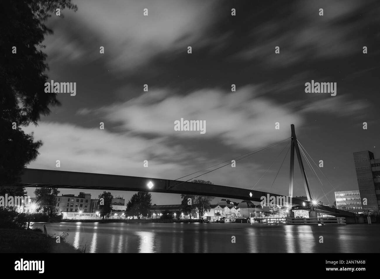 Un piccolo cavo alloggiato a ponte su un fiume per pedoni di notte, stelle, nuvole, lunga esposizione, nero e whiteA piccolo cavo alloggiato a ponte su un riv Foto Stock