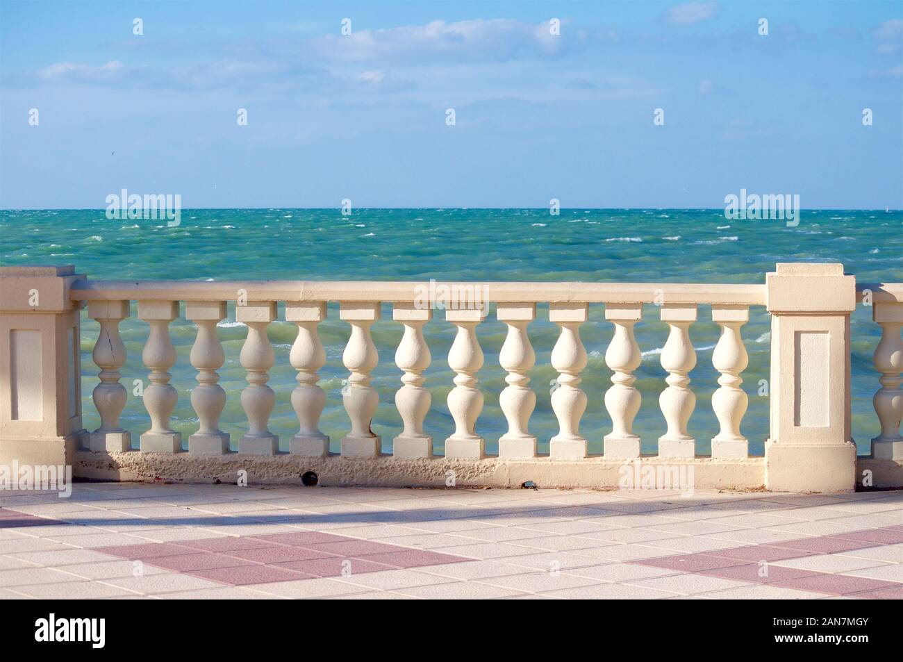 Passeggiata sul lungomare con un parapetto su una soleggiata giornata di vento dal mare oceano Foto Stock