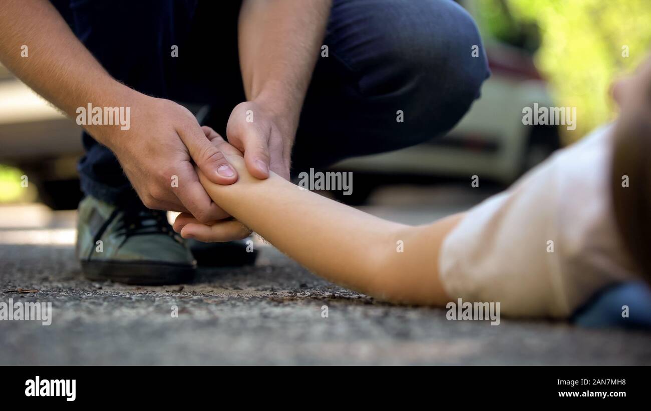 Azienda Man mano della ragazza distesa sulla strada, inconscio vittima di un incidente automobilistico, 911 Foto Stock
