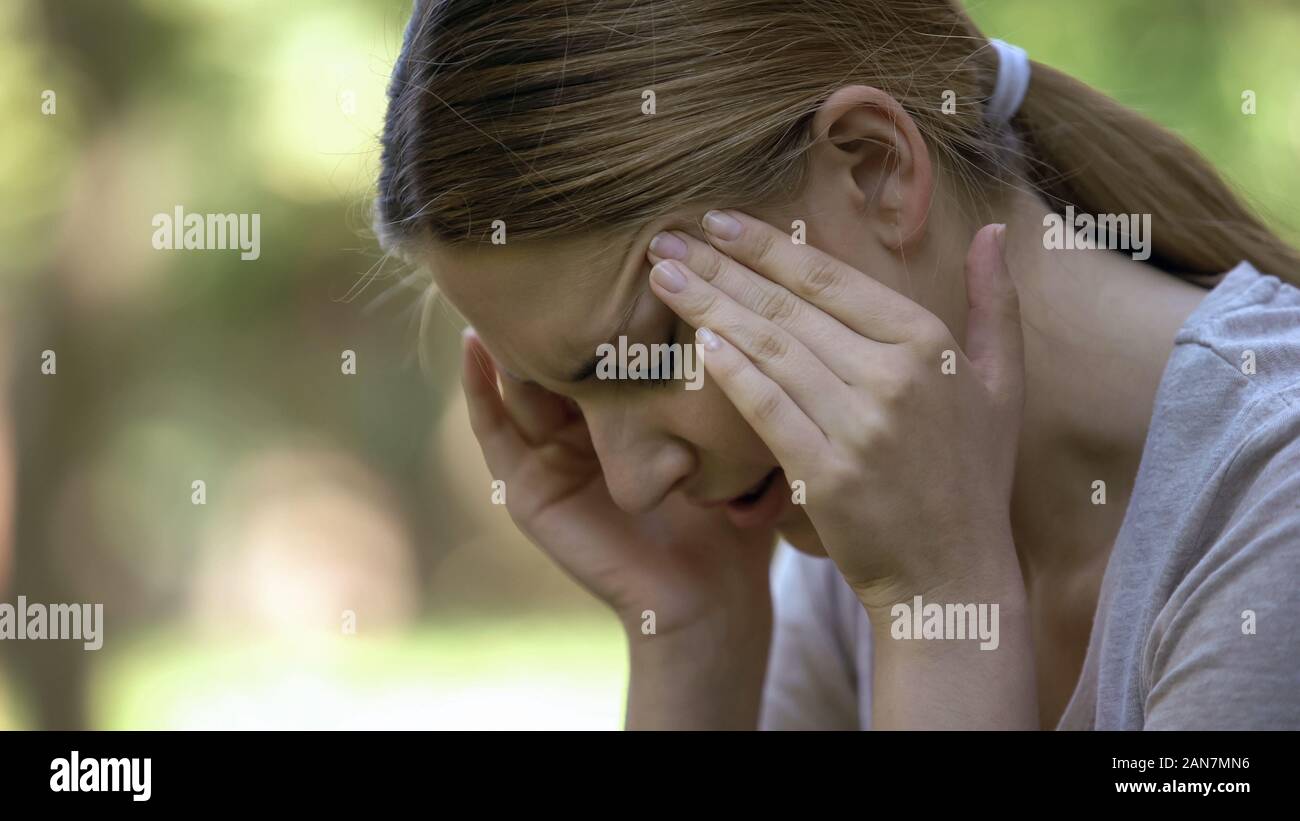 Giovane donna soffre di cefalea acuta, a preoccuparsi di fallimenti, giornata stressante Foto Stock