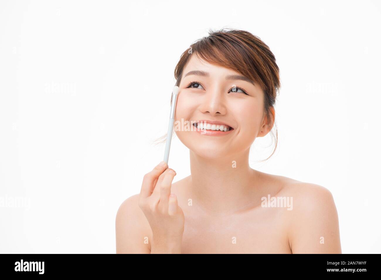 Una pelle perfetta. faccia bella donna asiatica applicando blusher trucco occhi colorati, cosmetici e trattamenti viso Foto Stock