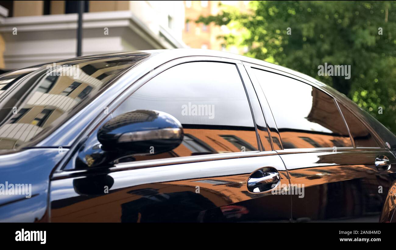 Auto di lusso con vetri colorati in piedi al parcheggio, la riflessione di imprenditore Foto Stock