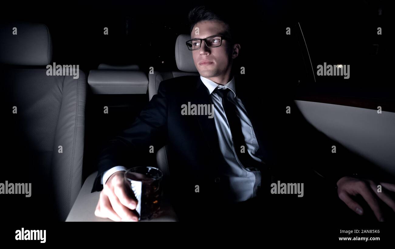 Millionaire bicchiere di brandy elite sul sedile posteriore della vettura, viaggio di lavoro Foto Stock