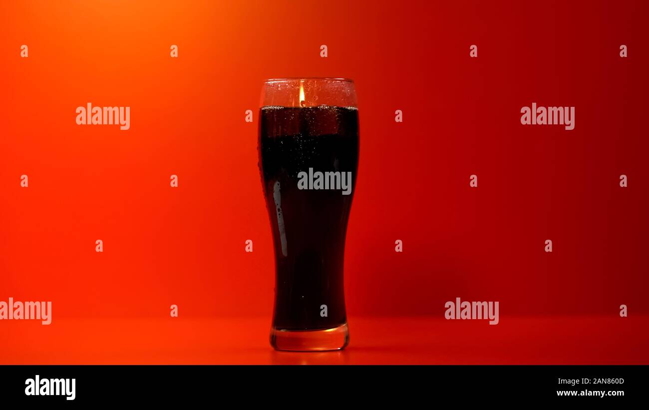 Bicchiere di soda isolato su sfondo rosso, rinfrescante ma malsana bevanda Foto Stock