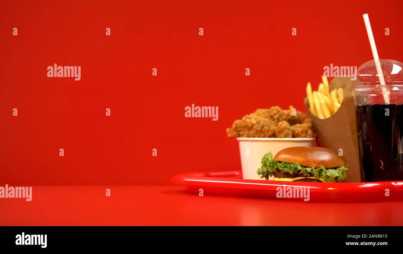 Ali fritte patatine e hamburger soda drink sul vassoio rosso, cibo da asporto Foto Stock