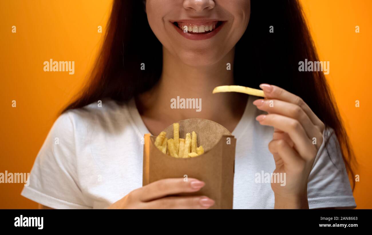 Felice ragazza con patatine fritte, i sapori artificiali e migliorato e il gusto delle tossicodipendenze Foto Stock
