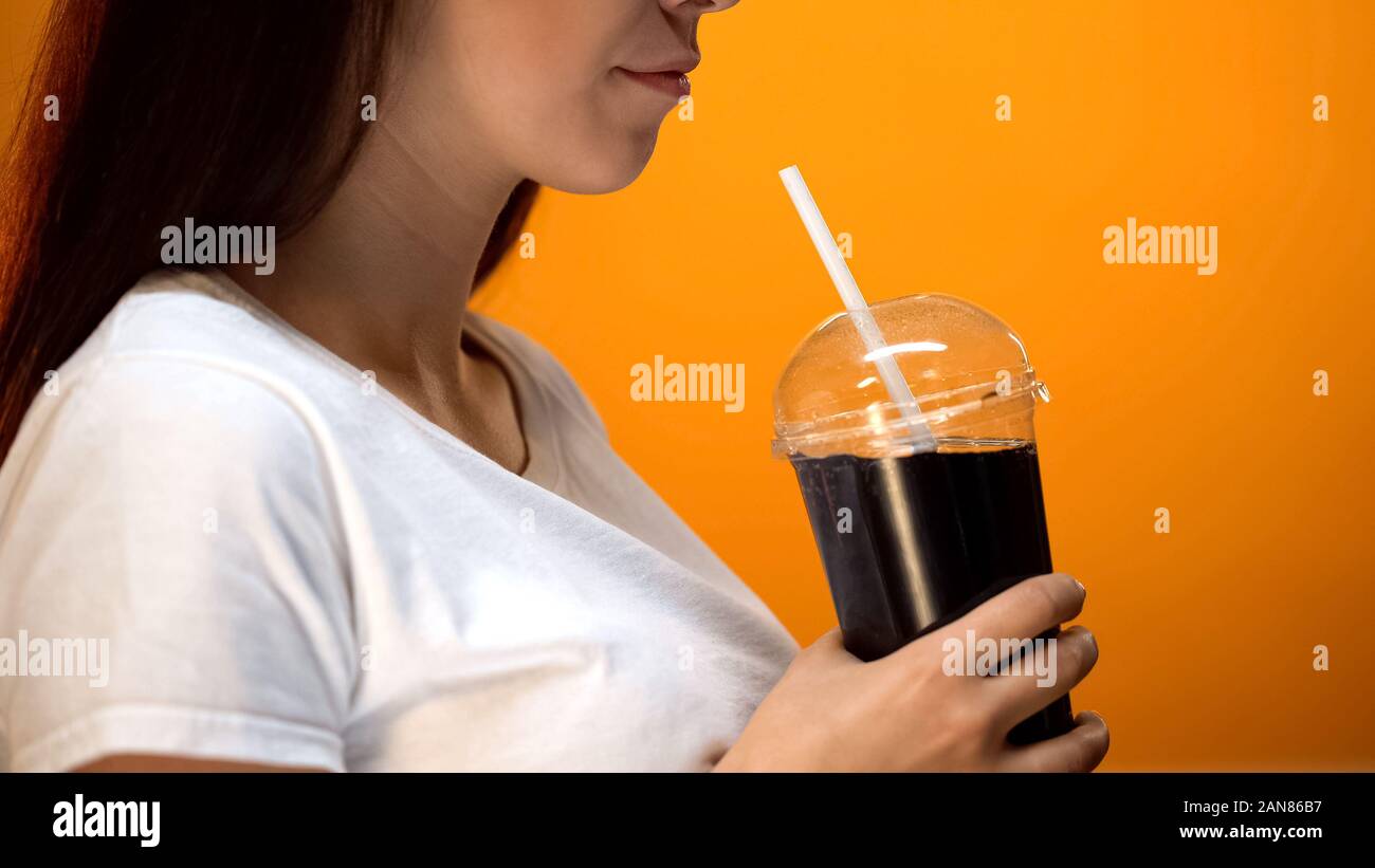 Giovane donna di soda di contenimento e sorridente, zucchero dipendenza, ad alto contenuto calorico bevande Foto Stock