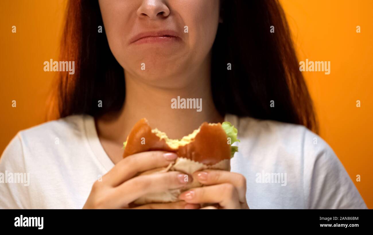Donna insoddisfatto con poco invitante hamburger, bassa qualità alimentare, primo piano Foto Stock