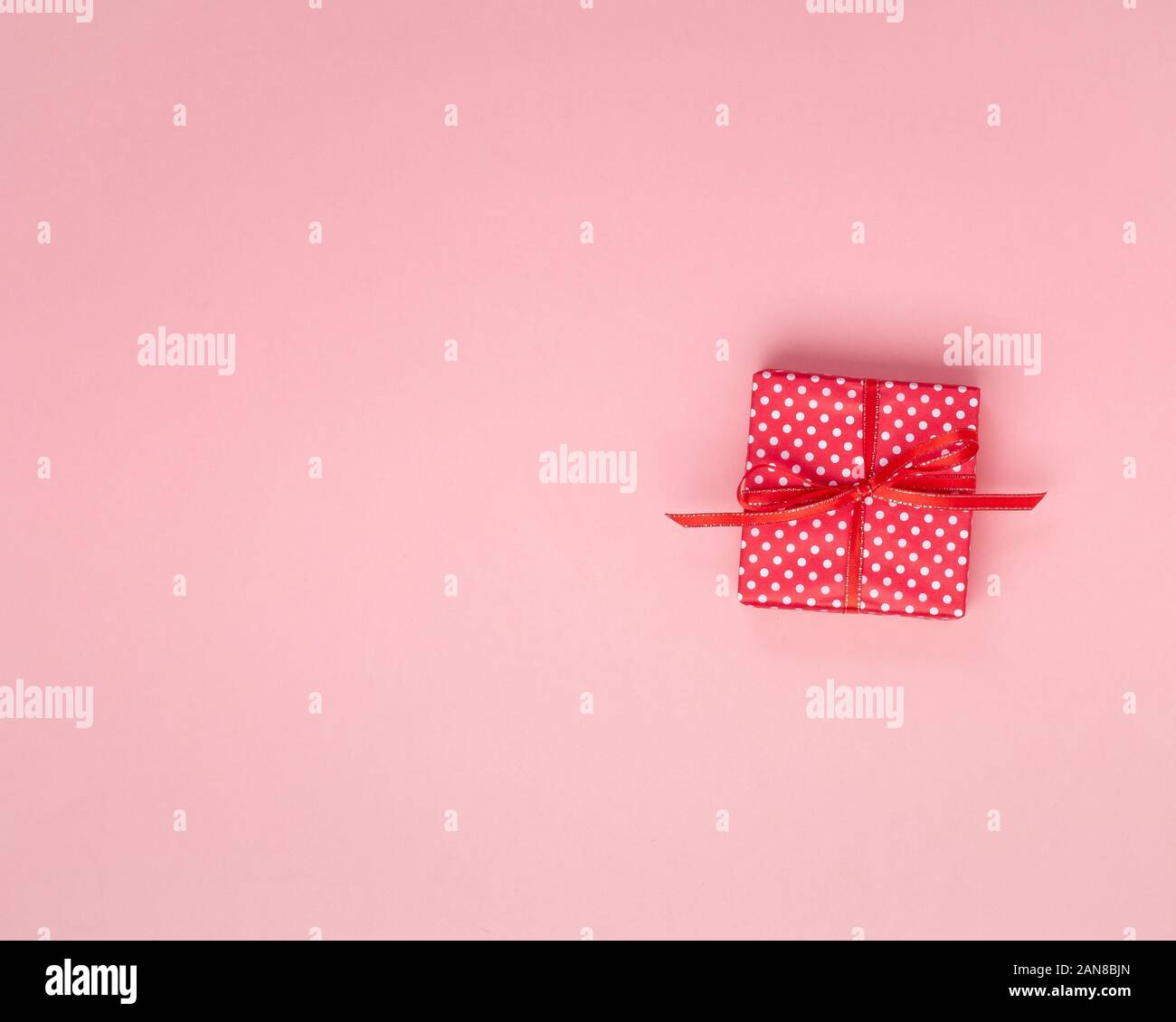 Regalo in confezione regalo rossa con fiocco, sfondo rosa, vista dall'alto, lo spazio vuoto per il testo. Foto Stock