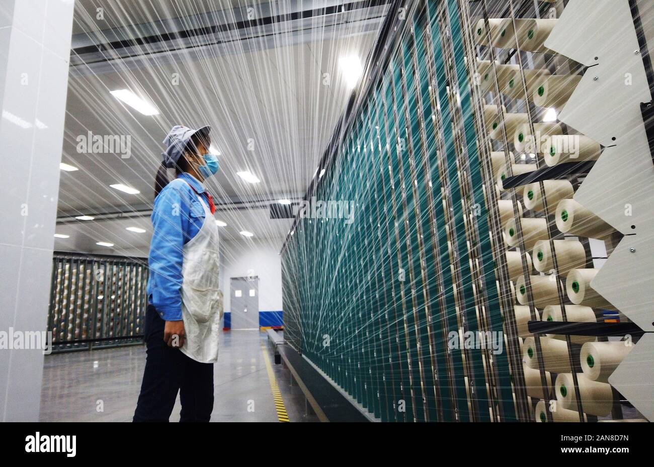 Un lavoratore cinese controlla una macchina di filato in un impianto tessile in Zouping, Binzhou City, est della Cina di Provincia di Shandong su gennaio 15th, 2020. Foto Stock