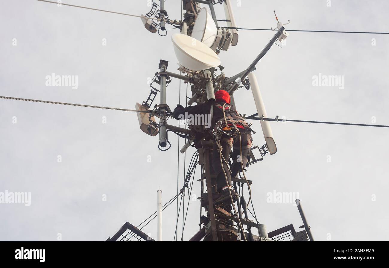 Elettricista uomo o alpinista arrampicata su palo antenna per ispezione Foto Stock