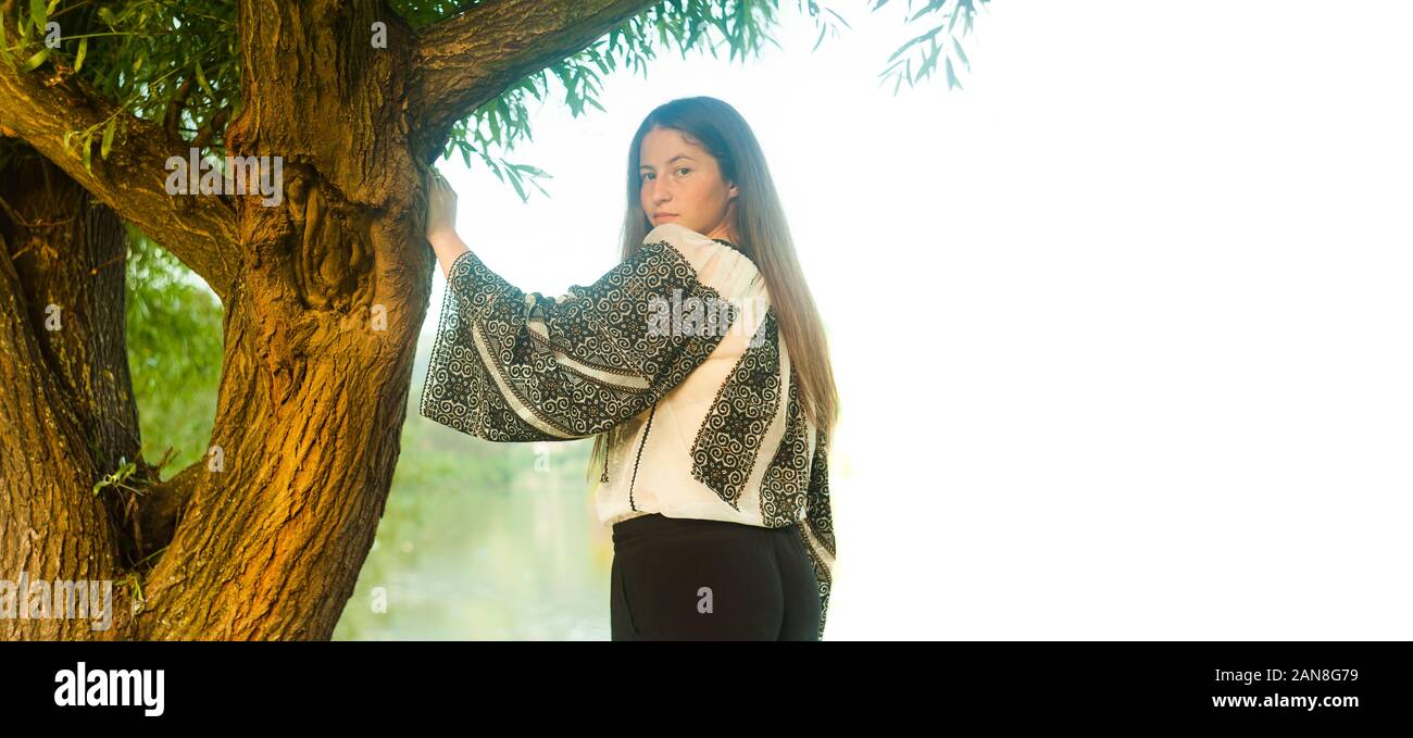 Bellissima ragazza e l'albero. Il rumeno tradizionale costume isolato su bianco Foto Stock