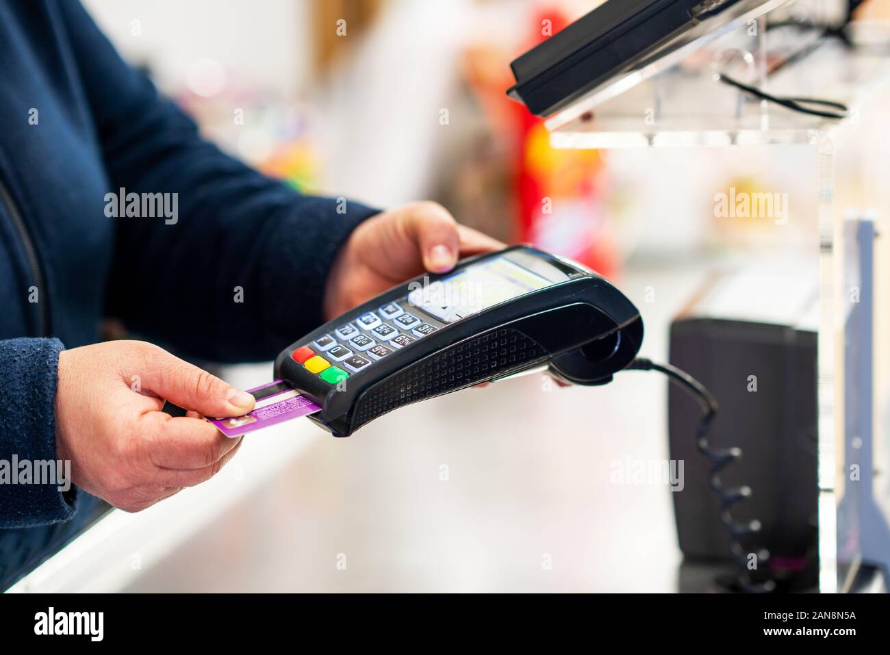 Mano con creditcard scorri attraverso il terminale POS per il pagamento in un negozio. Foto Stock