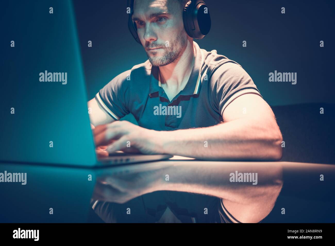 Caucasian Web Content Creator che indossano le cuffie al lavoro sul suo computer portatile. Moderne tecnologie Internet. Foto Stock