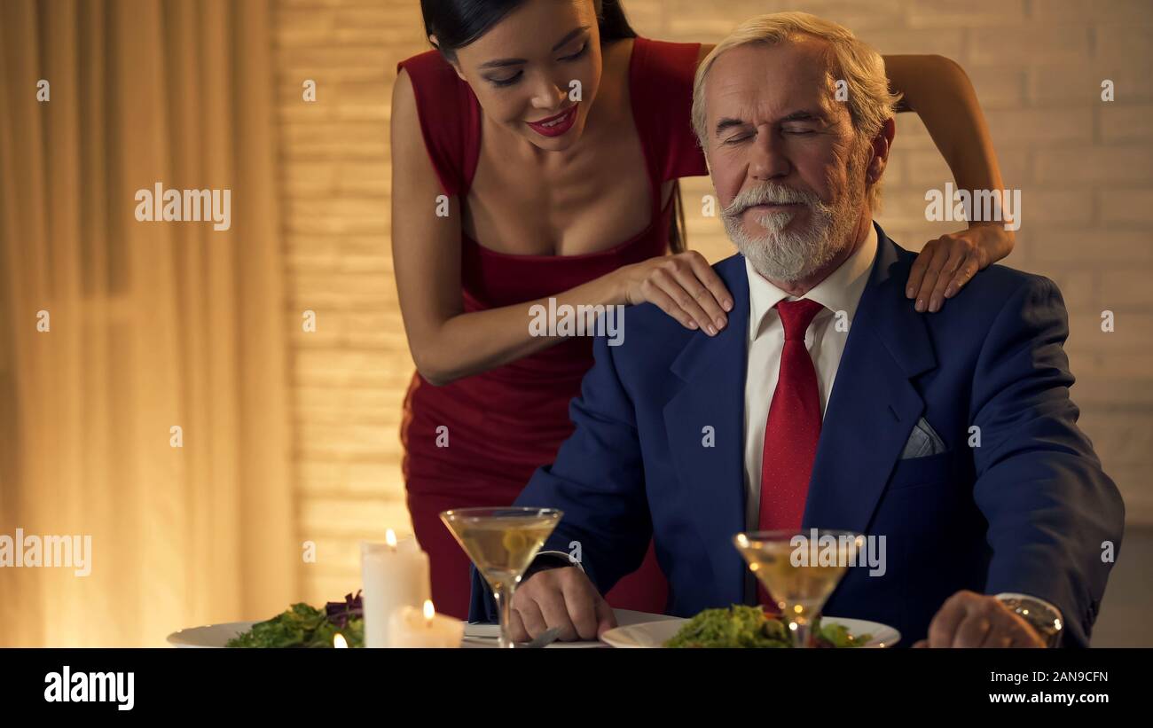 Donna attraente massaggiando le spalle dell uomo vecchio paio di vicinanza, l affetto Foto Stock