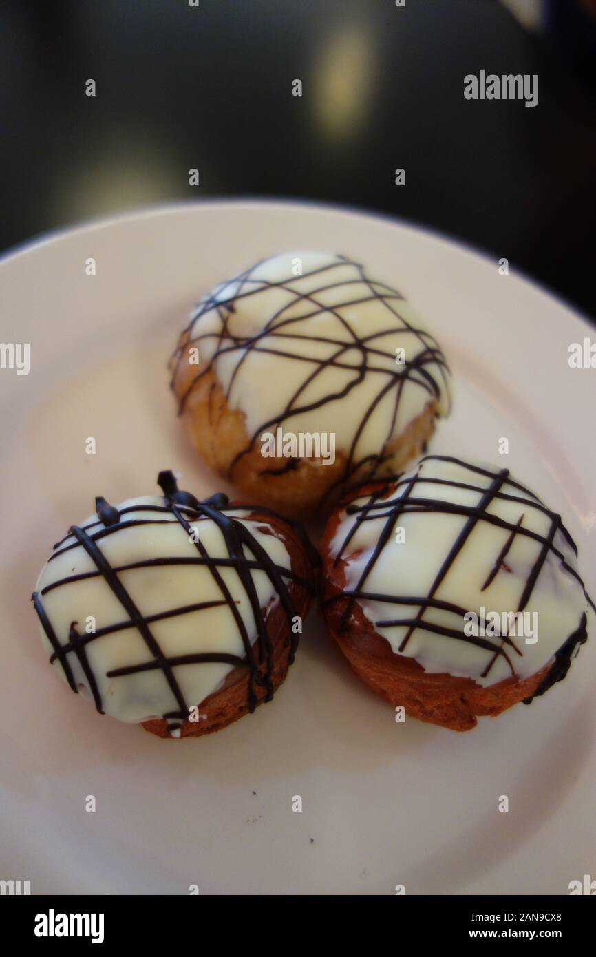 Tre bianchi Profiterole al cioccolato spruzzata con cioccolato fondente e riempito di crema Patissiere nel Buffet all'Azul Beach Resort Hotel, Puerto Morelos Foto Stock