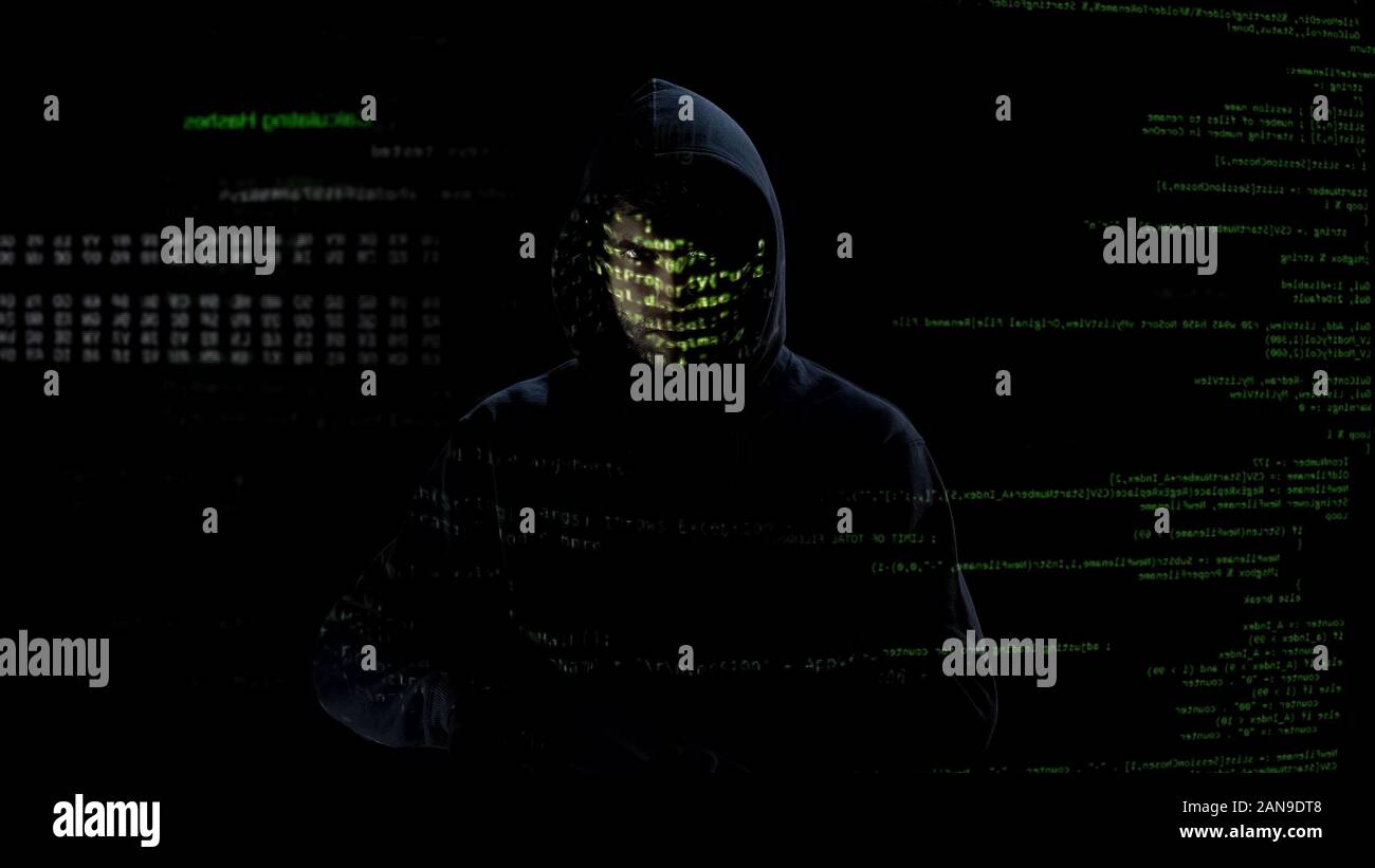 In incognito un uomo guarda i codici e numeri sulla schermata, attacco hacker, criminalità informatica Foto Stock