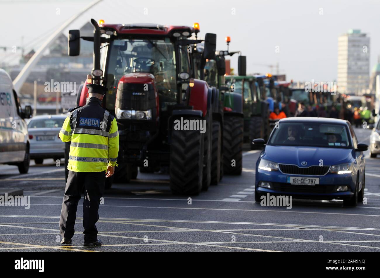 Un membro di un garda Siochana sorge tra i trattori e il traffico sulle banchine nel centro della città di Dublino come una manifestazione di protesta da parte degli agricoltori al di sopra dei prezzi da ottenere per i loro prodotti continua. Foto Stock