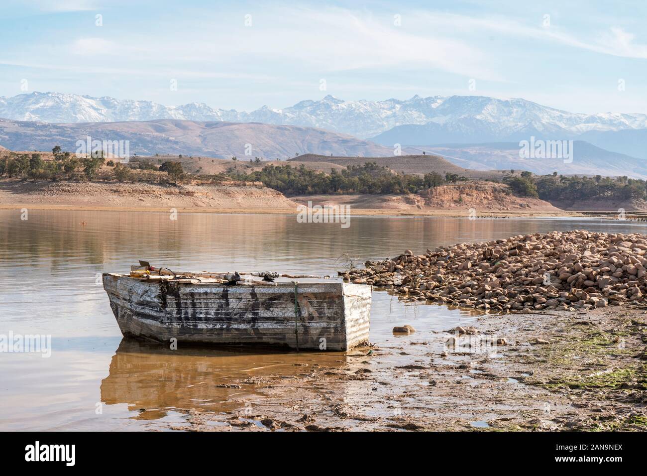 La barca di legno sulla riva del lago Takerkoust con montagne Atlas in background, Marrakech, Marocco Foto Stock