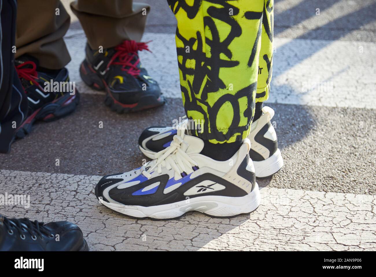 Milano, Italia - 12 gennaio 2019: l'uomo con il bianco e nero Reebok sneakers e verde giallo pantaloni prima di Salvatore Ferragamo fashion show, Milano Fas Foto Stock