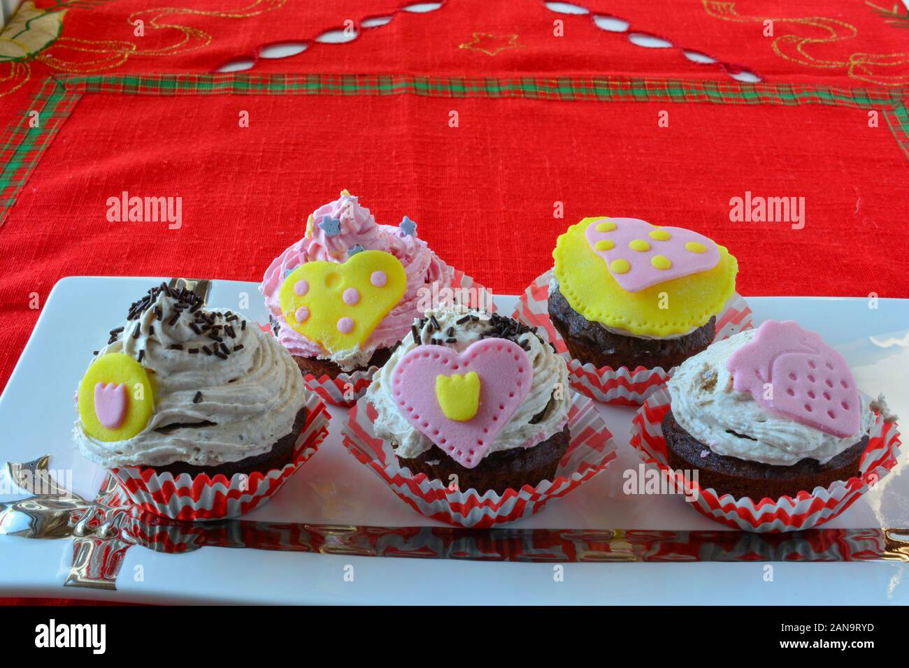 Amore muffin, colorato tortine decorate con cuori di marzapane servita in ceramica bianca piattino, vista laterale Foto Stock