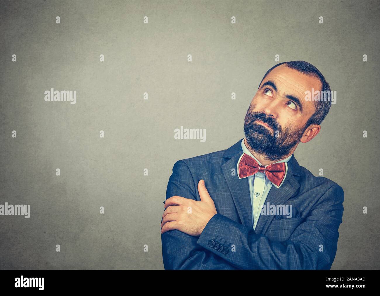 Ritratto di pensare uomo bello pensieroso guardando in alto a destra. Gara di misto modello barbuto isolate su studio grigio Sfondo a parete con copia spazio. Foto Stock