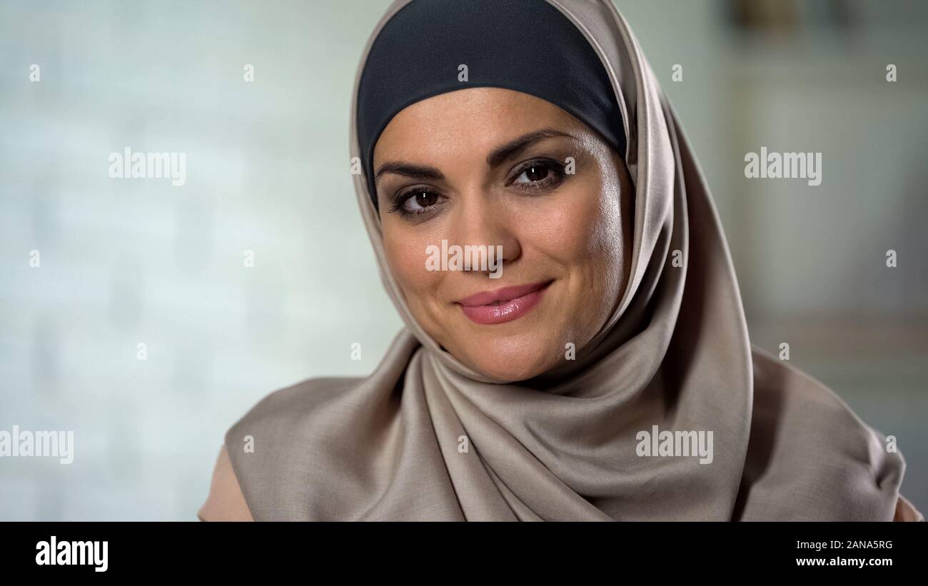 Modesto donna musulmana in hijab guardando la fotocamera con il sorriso misterioso, primo piano Foto Stock