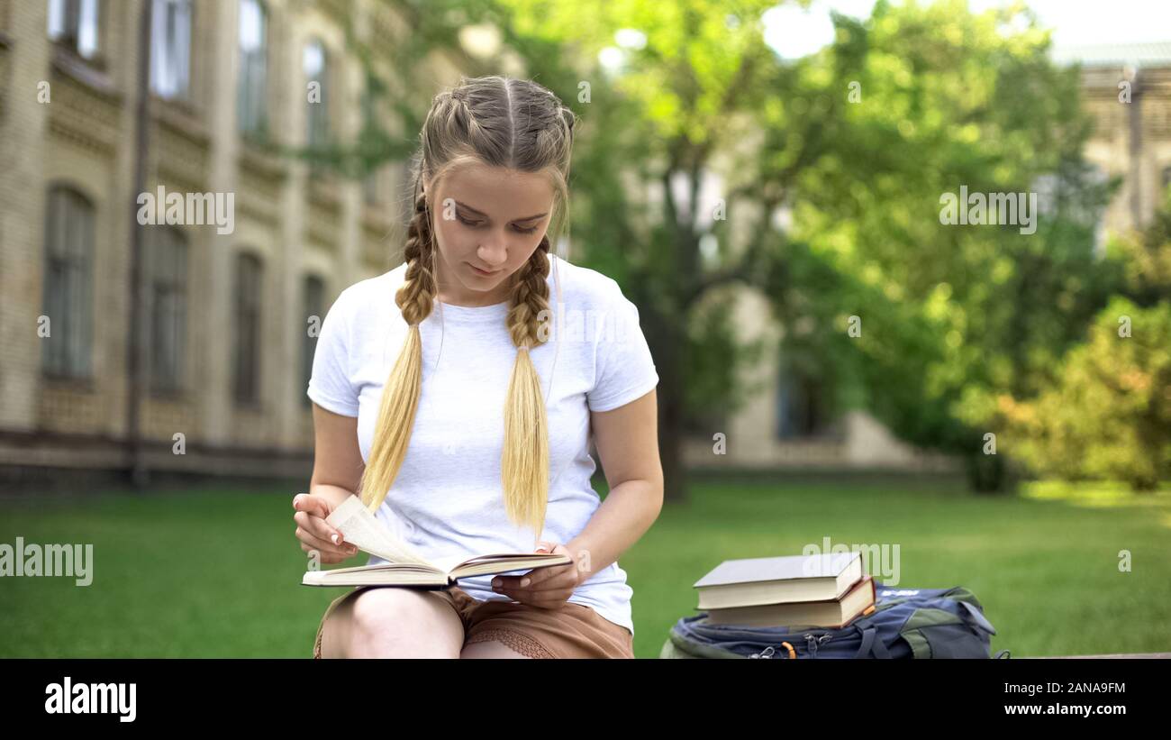Giovane donna libro di lettura sul banco del campus, preparare i compiti, istruzione Foto Stock