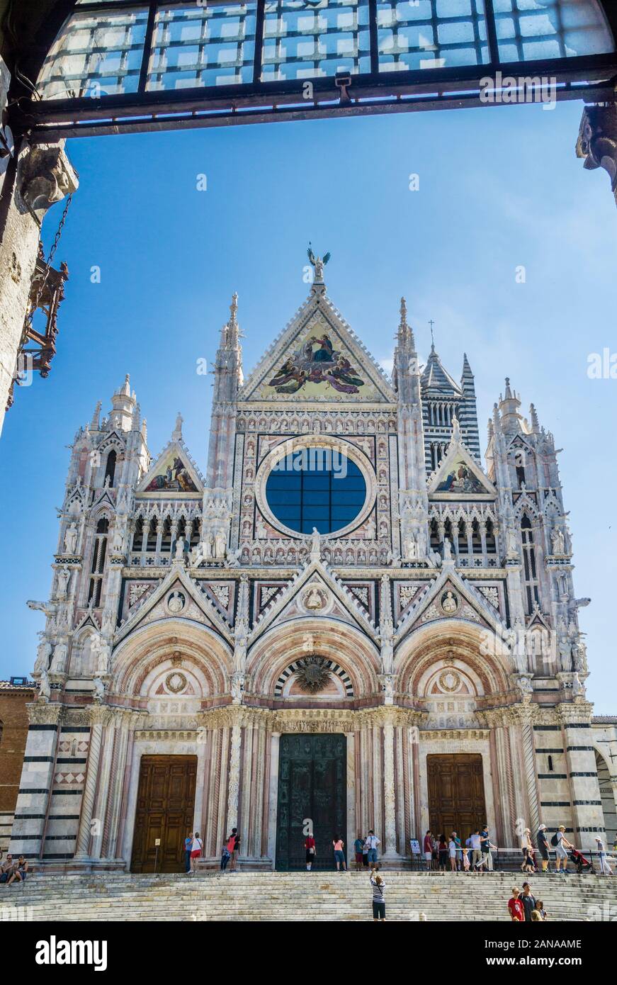 La facciata del Duomo di Siena con strisce alternate di colore bianco e verde-marmo nero con le sue tre portale, agendo come la principale porta d ingresso al Duomo, Foto Stock