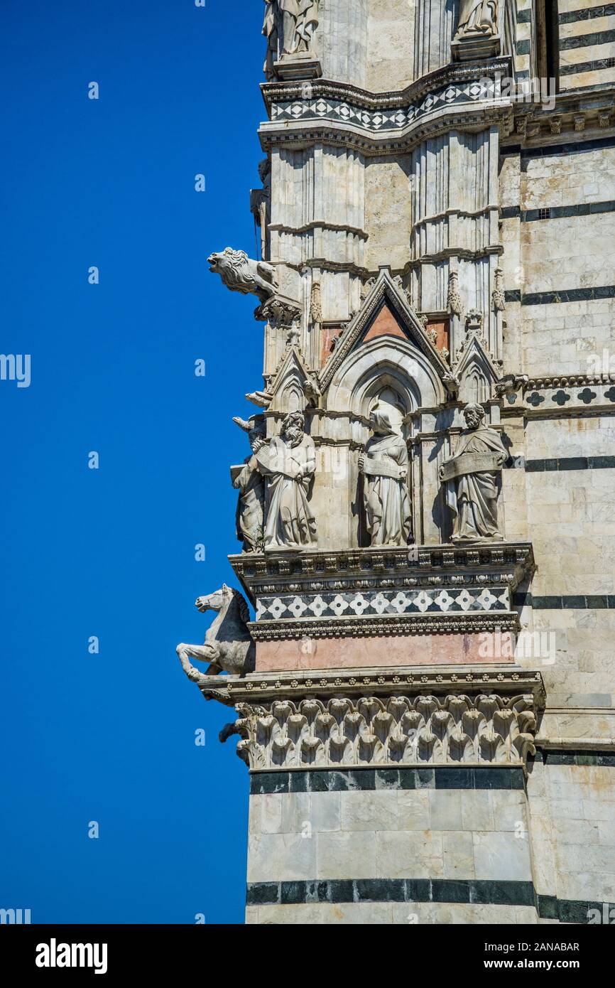 Mascheroni e santi sulla facciata del Duomo di Siena, Siena, Toscana, Italia Foto Stock