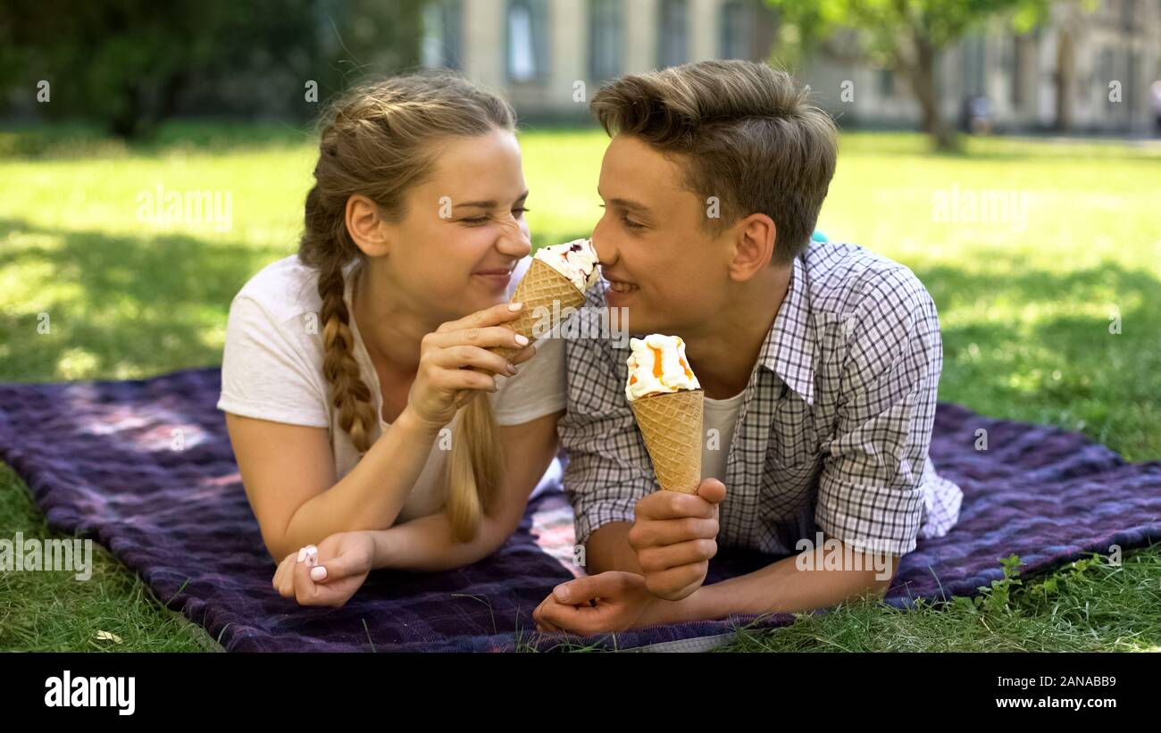 Teens ingannare intorno con gelato, giacente su plaid nel parco, divertirsi insieme Foto Stock