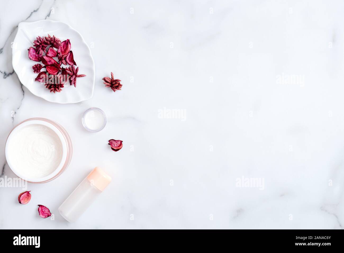 Cosmetici naturali Crema lozione e su sfondo marmo rosso con petali di fiori. La bellezza del prodotto organico. Vista superiore, piana, laici copia spazio. Dermocosmesi e bo Foto Stock