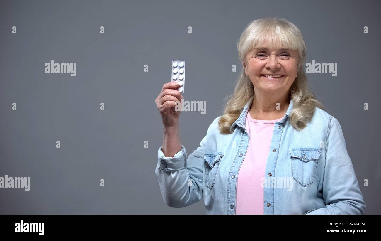 Allegro senior lady mostra pillole, cuore efficaci farmaci antivirali Foto Stock