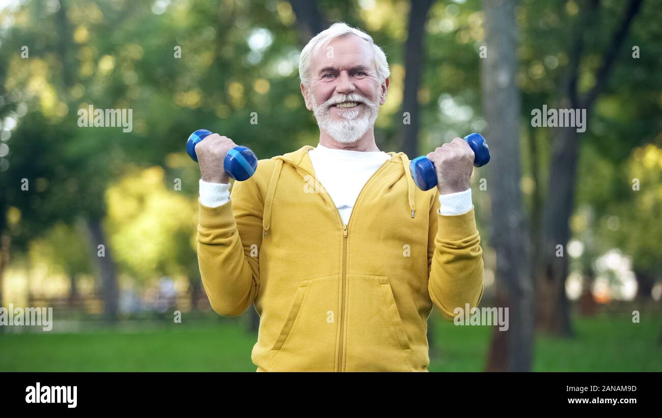 Grigio-uomo barbuto il sollevamento pesi nel parco, attività per il tempo libero, healthcare Foto Stock